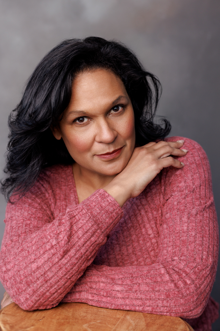 Headshot of Maya Francine Thomas in a pink sweater, direct gaze